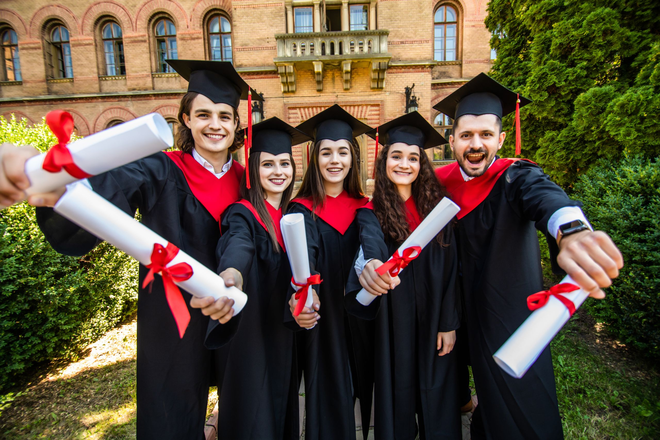 Happy graduation day. 5 graduates hold his graduate diplomas in their hands at University
