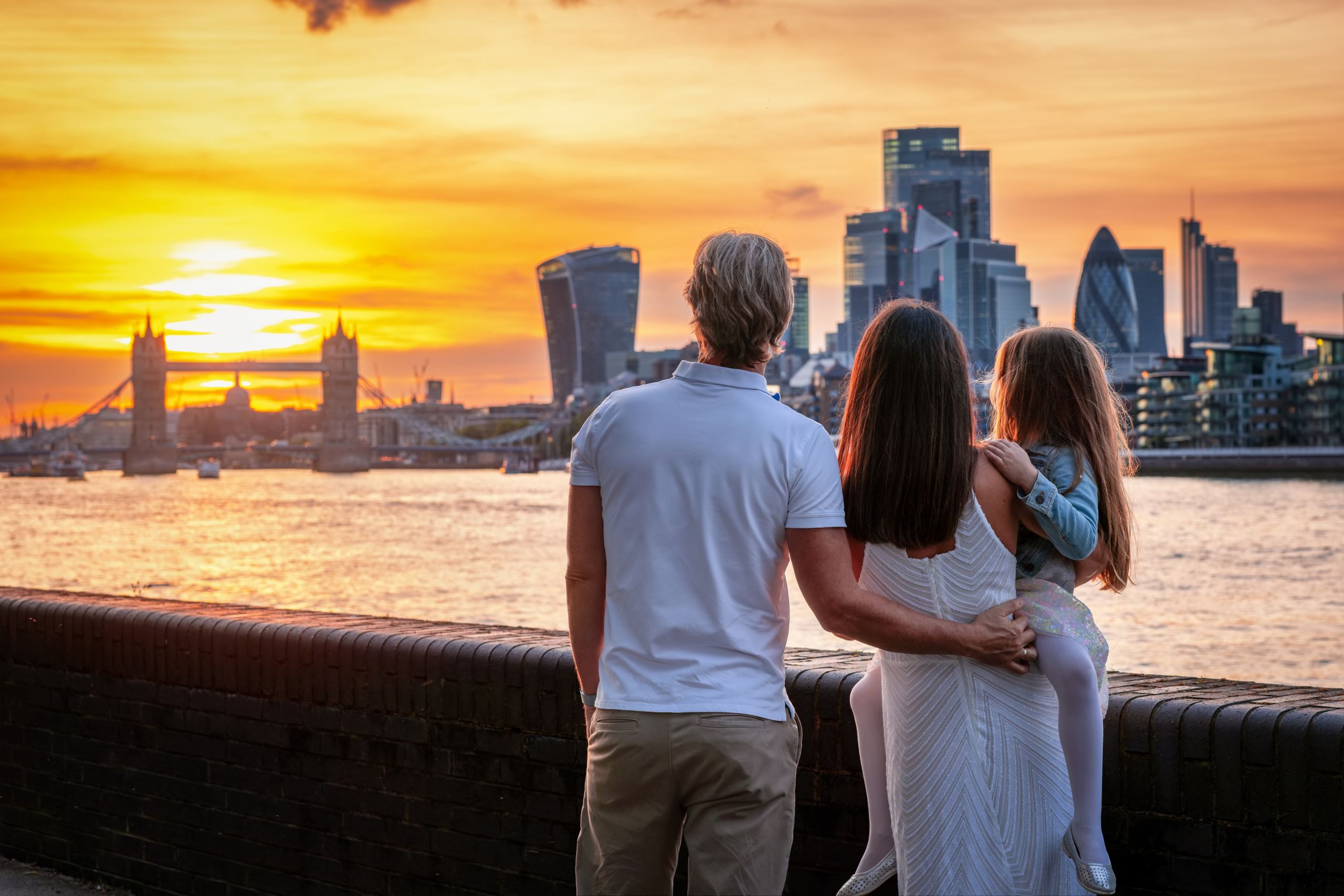 A tourist family on a city trip looks at the skyline of London during sunset time