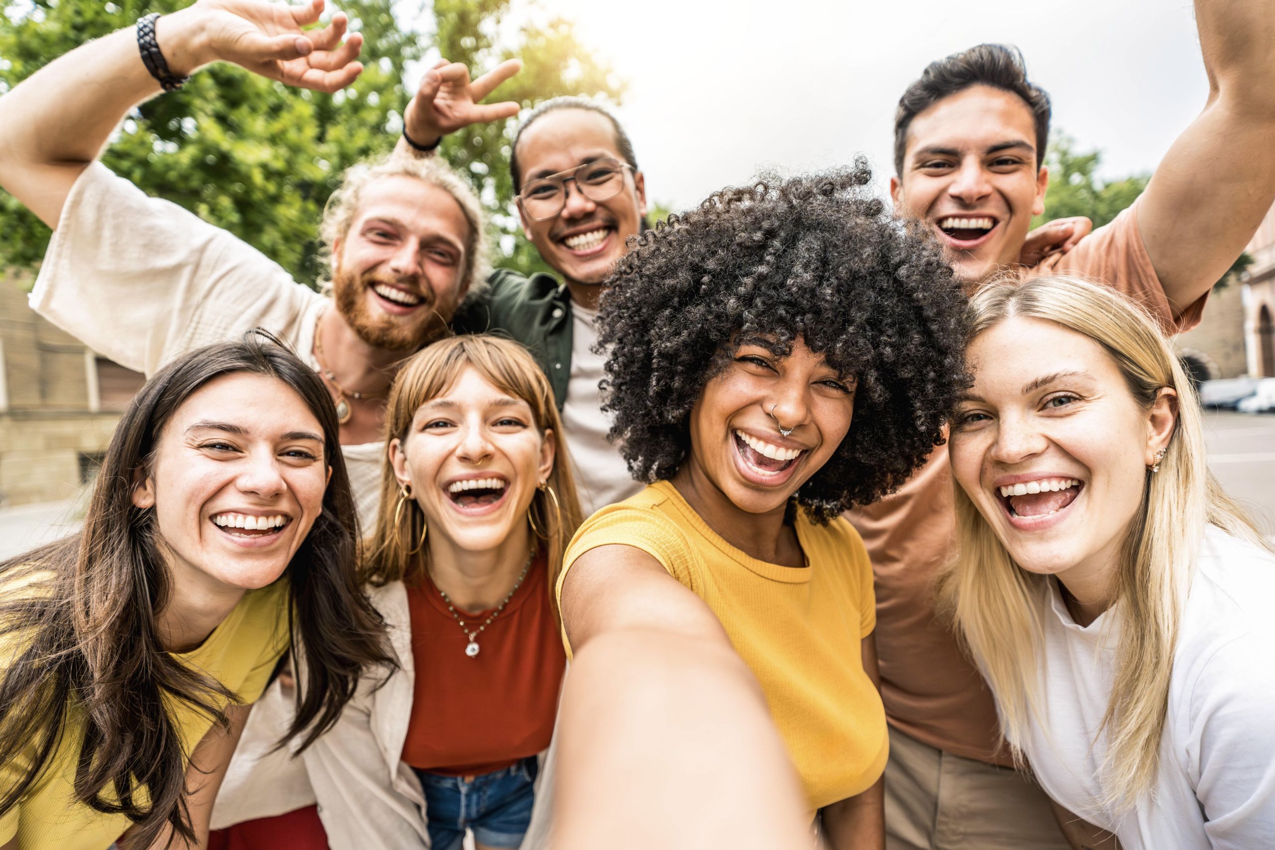 Multicultural friends smiling at camera together outside – Happy young people taking selfie with smart mobile phone device walking on city street – Youth community and technology concept